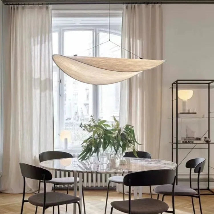 Adara pendant light suspended over a round dining table by tall window