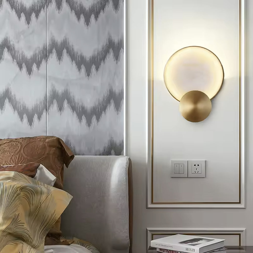 Alabaster and gold wall sconce beside a bed in a panelled bedroom