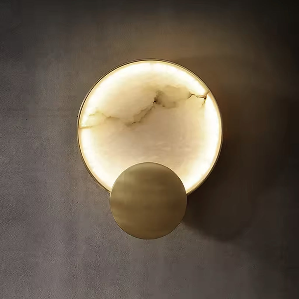 Natural alabaster disc wall sconce with a brushed gold sphere, switched on