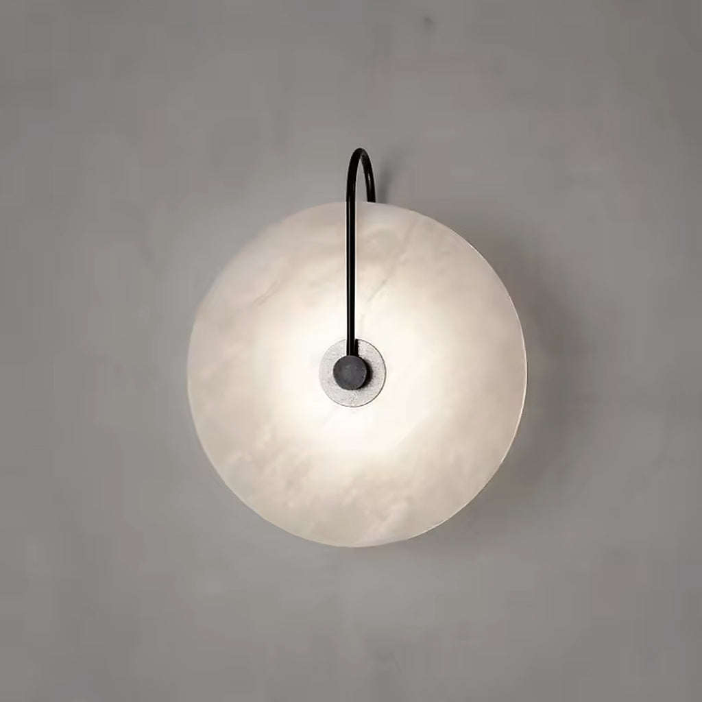 Natural alabaster disc wall sconce on a black arm, switched on