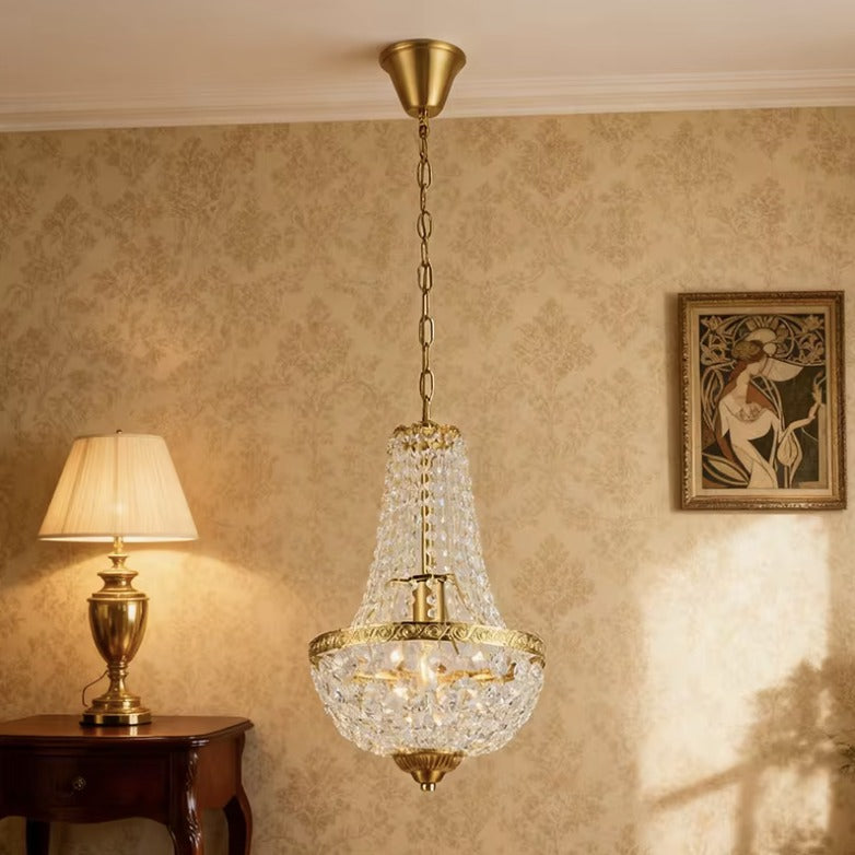 Antique crystal chandelier in brass hanging in a living room with patterned wallpaper