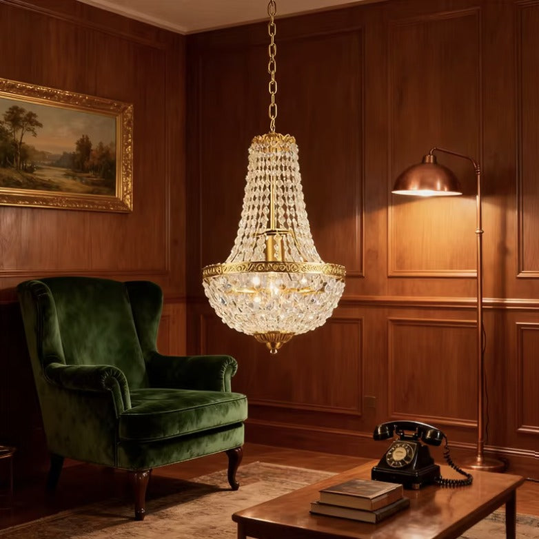 Antique crystal chandelier in a wood panelled study with a green velvet armchair