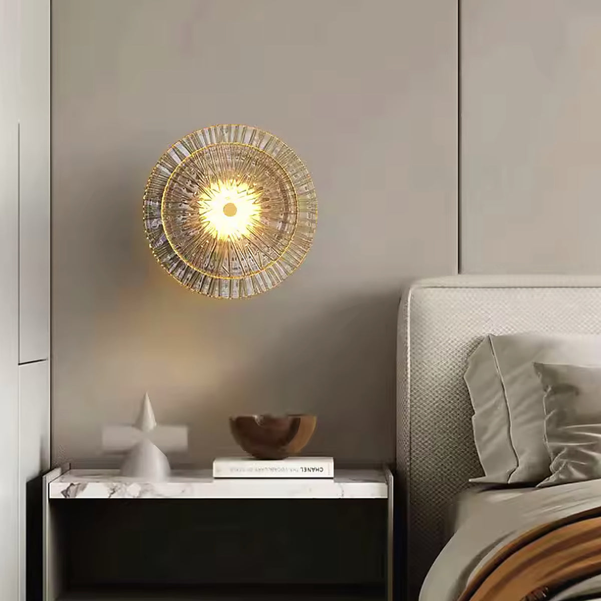 Art deco glass wall sconce lit above a bedside table