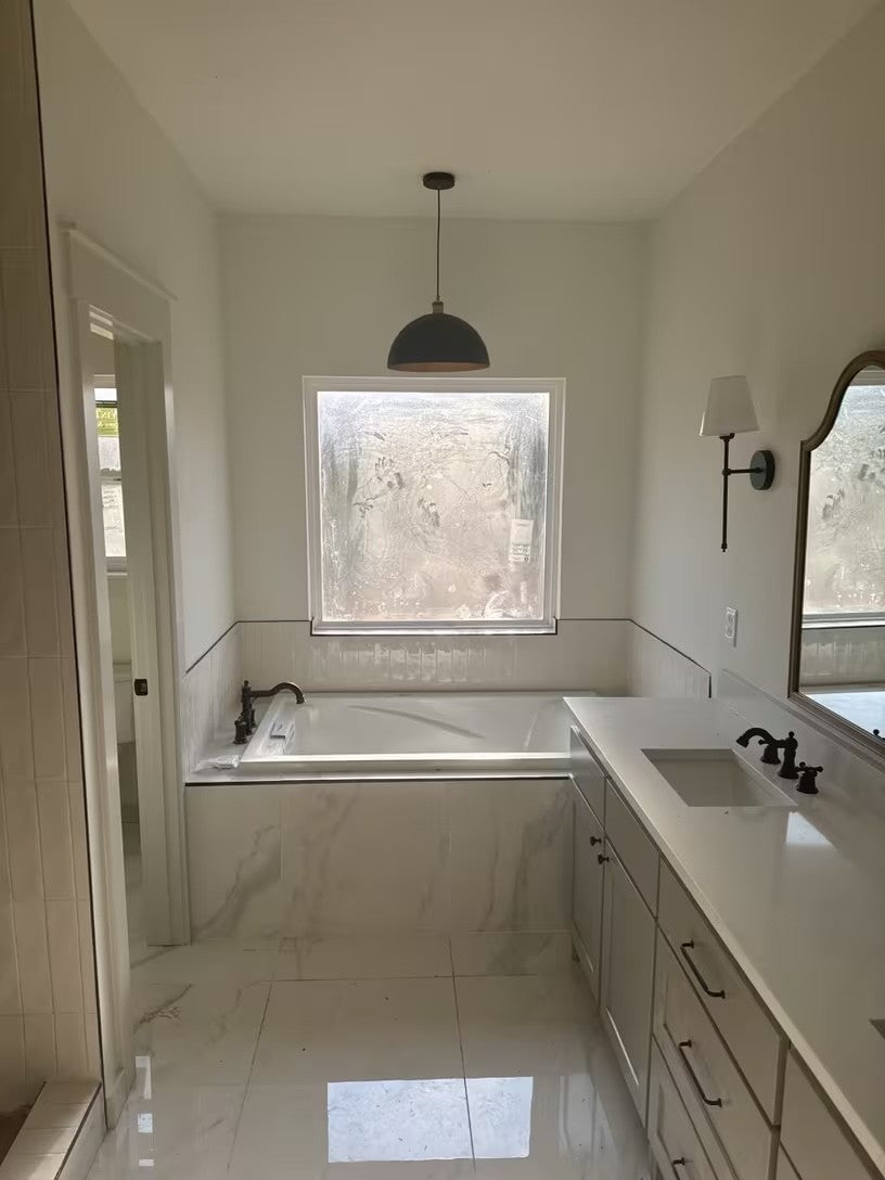 Black and gold dome pendant light above a bathtub in a white bathroom