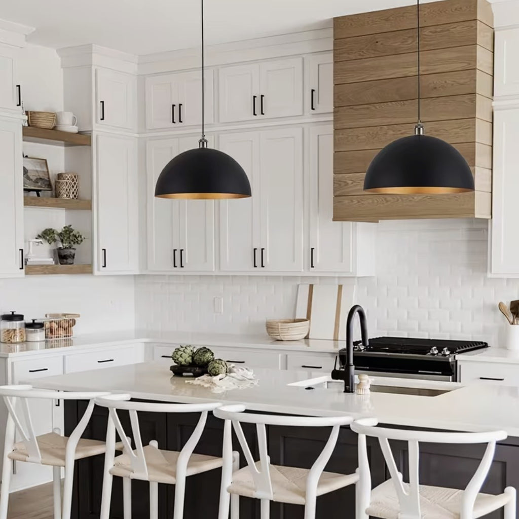Two black and gold dome pendant lights above a white kitchen island