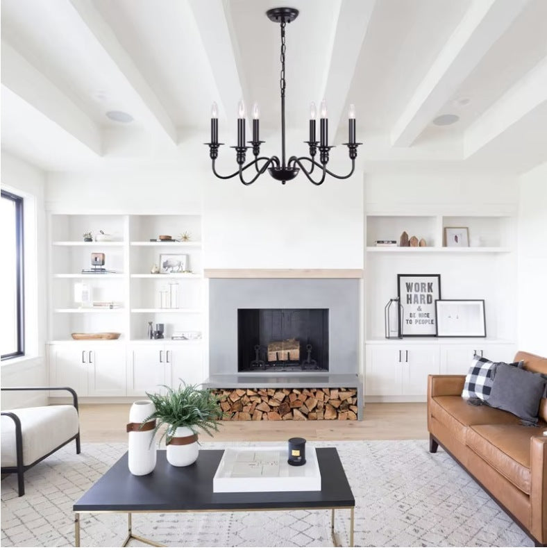 Black farmhouse candle chandelier in a living room with a fireplace and leather sofa