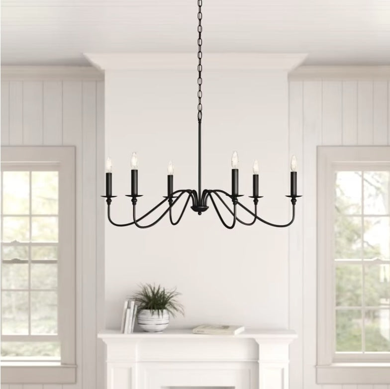 Black farmhouse candle chandelier above a white fireplace in a panelled room