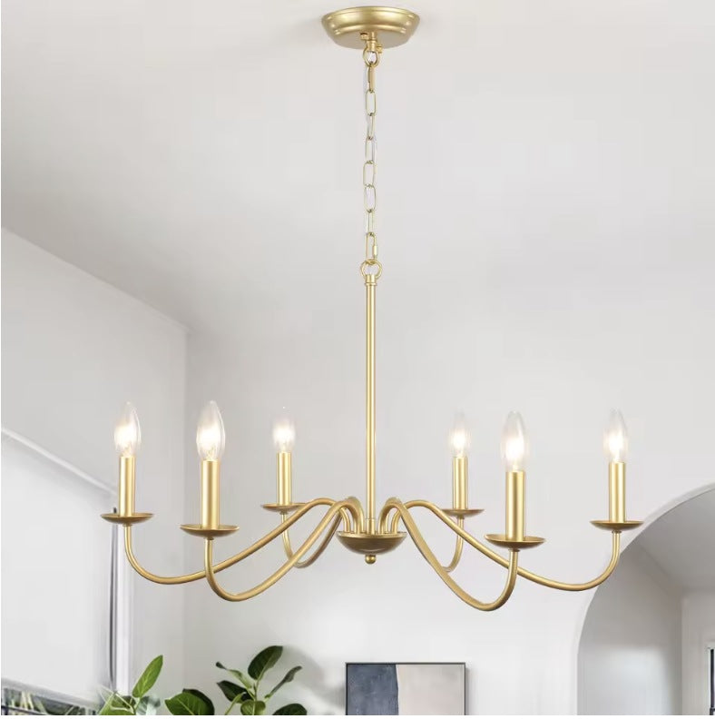 Gold farmhouse candle chandelier in a bright hallway with an arched doorway