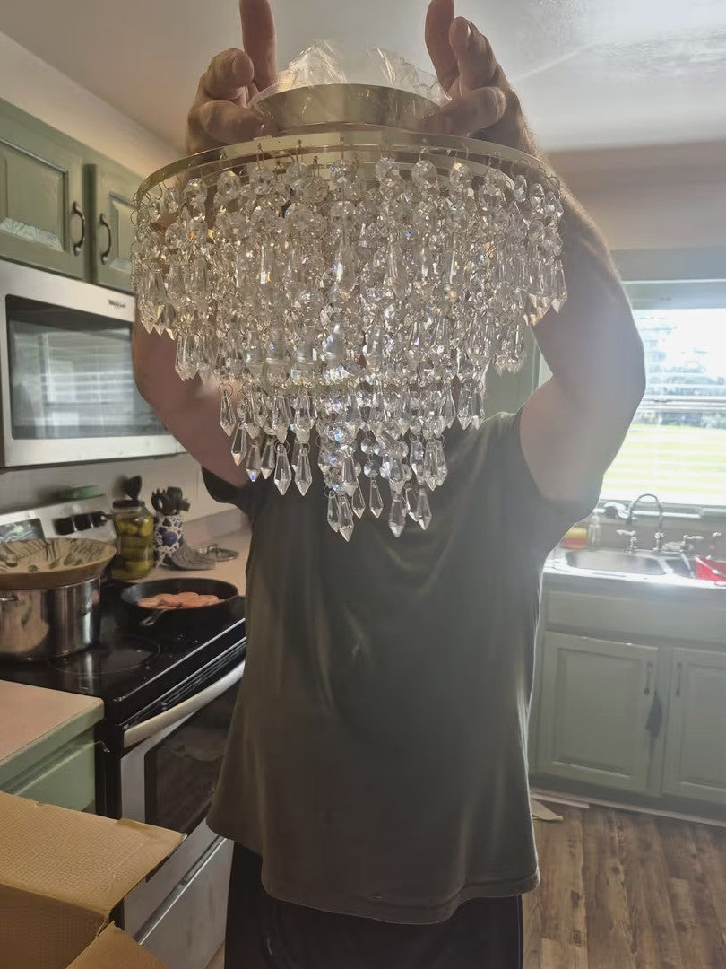 Gold crystal chandelier ceiling light held before installation in a kitchen