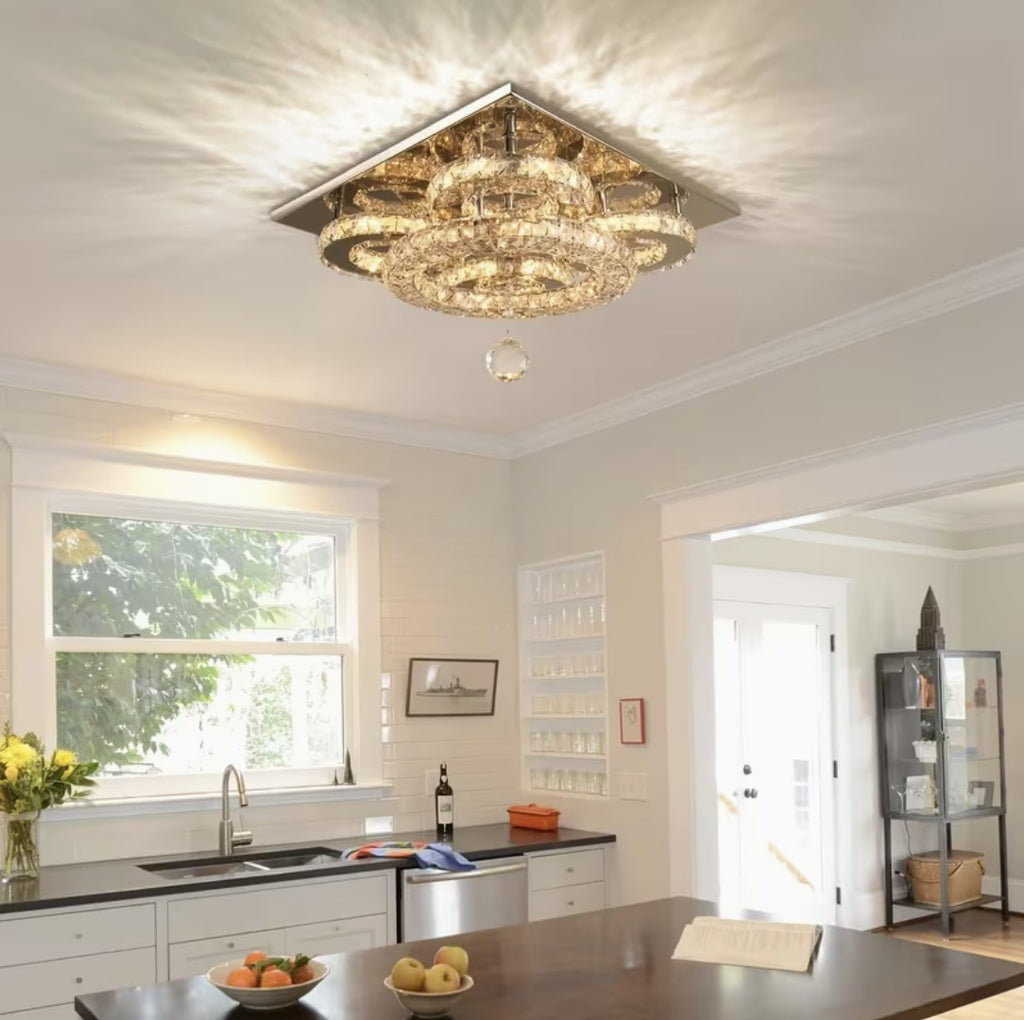 Flush mount crystal chandelier lit in warm light above a kitchen counter
