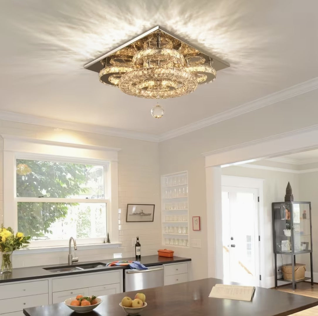 Flush mount crystal chandelier lit in warm light above a kitchen counter