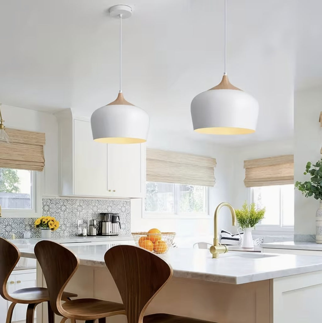 Two white kitchen island pendant lights above a marble island