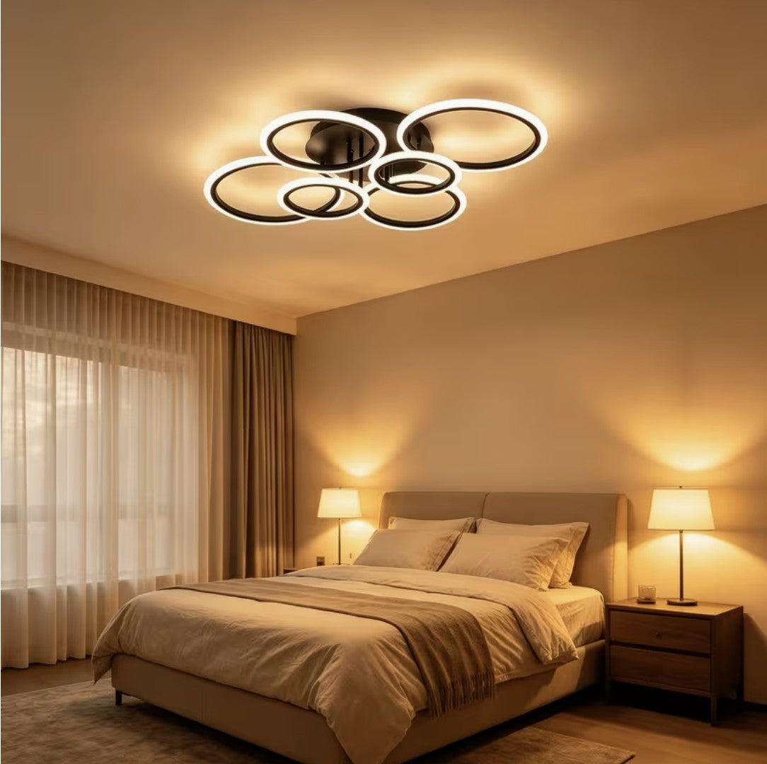 Black LED ring ceiling light above a bed in warm light