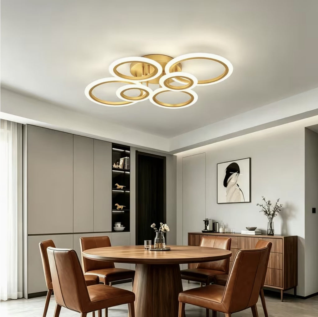 Gold LED ring ceiling light above a round wooden dining table