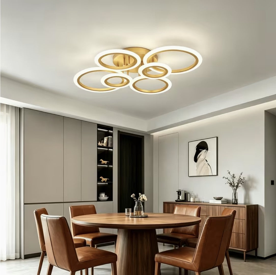 Gold LED ring ceiling light above a round wooden dining table