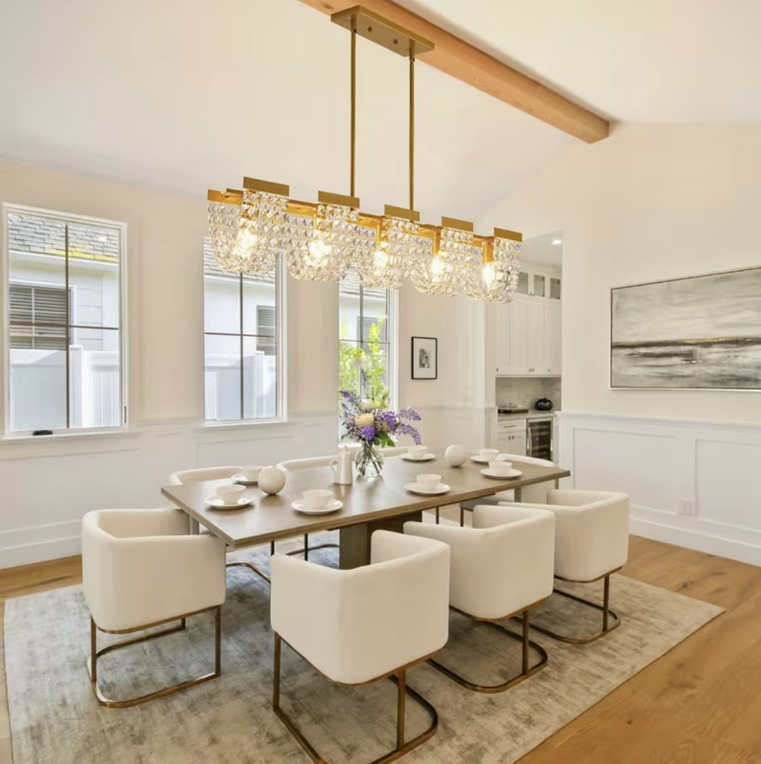 Linear crystal chandelier above a dining room table, gold finish