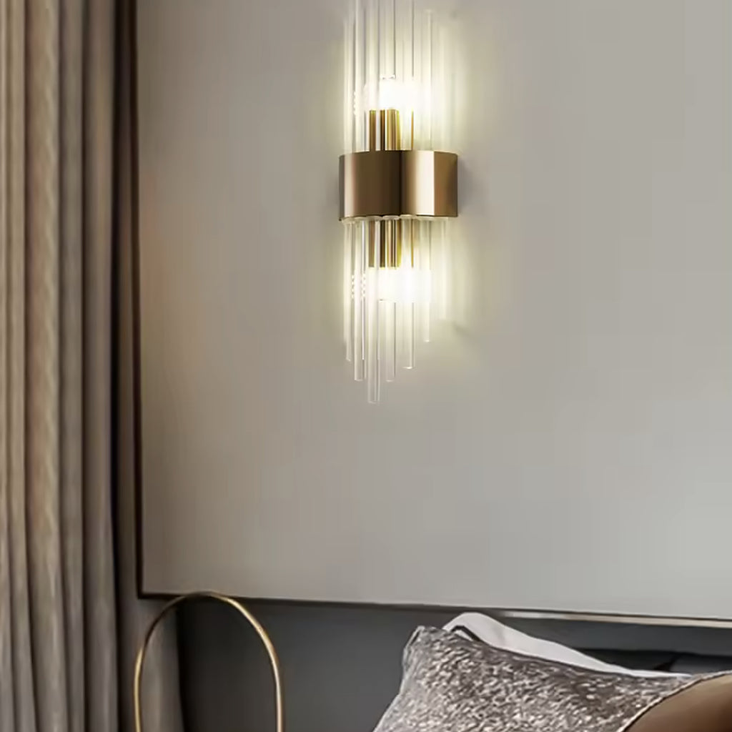 Gold linear glass rod wall sconce above a bedside table