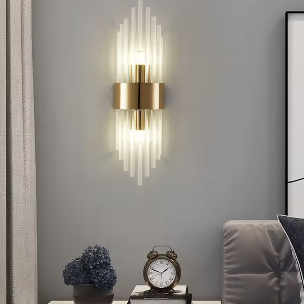 Gold linear glass rod wall sconce switched on above a console