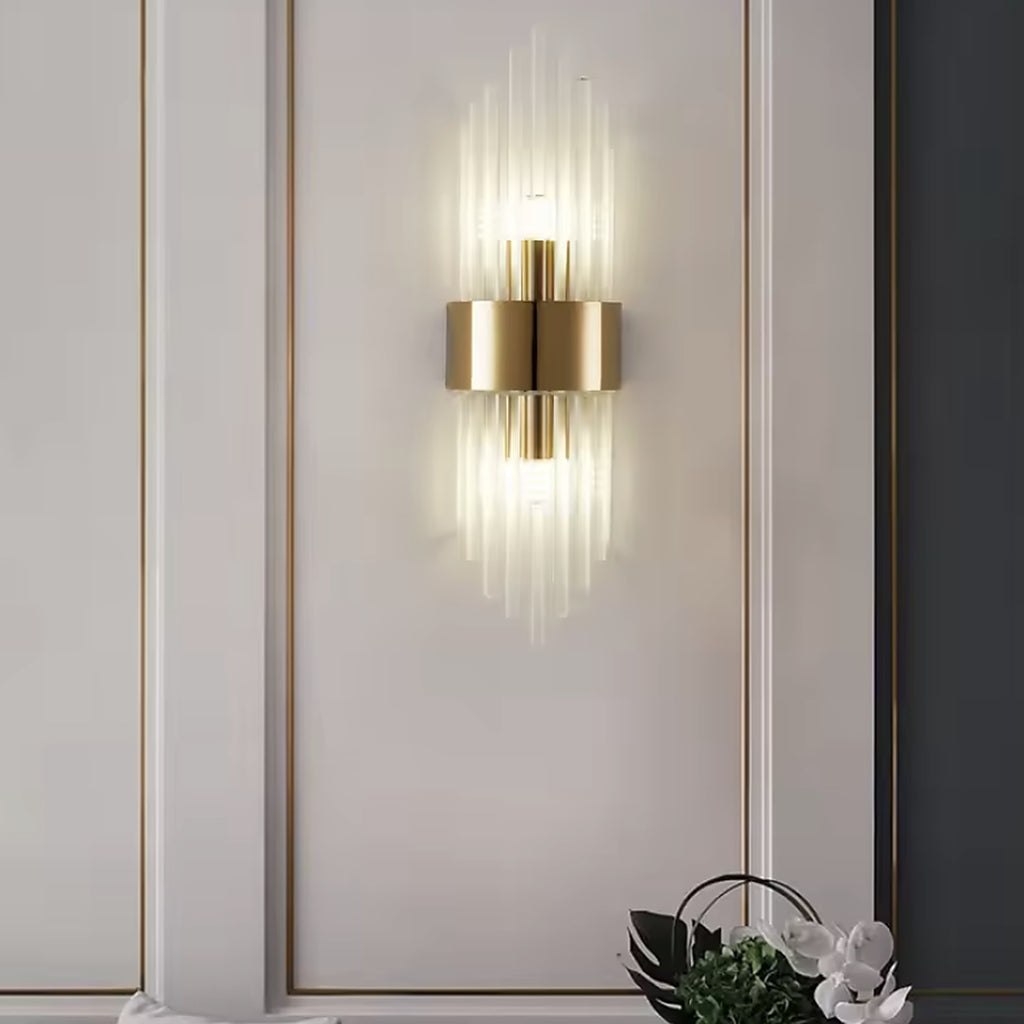 Gold linear glass rod wall sconce on a panelled wall above a green sofa