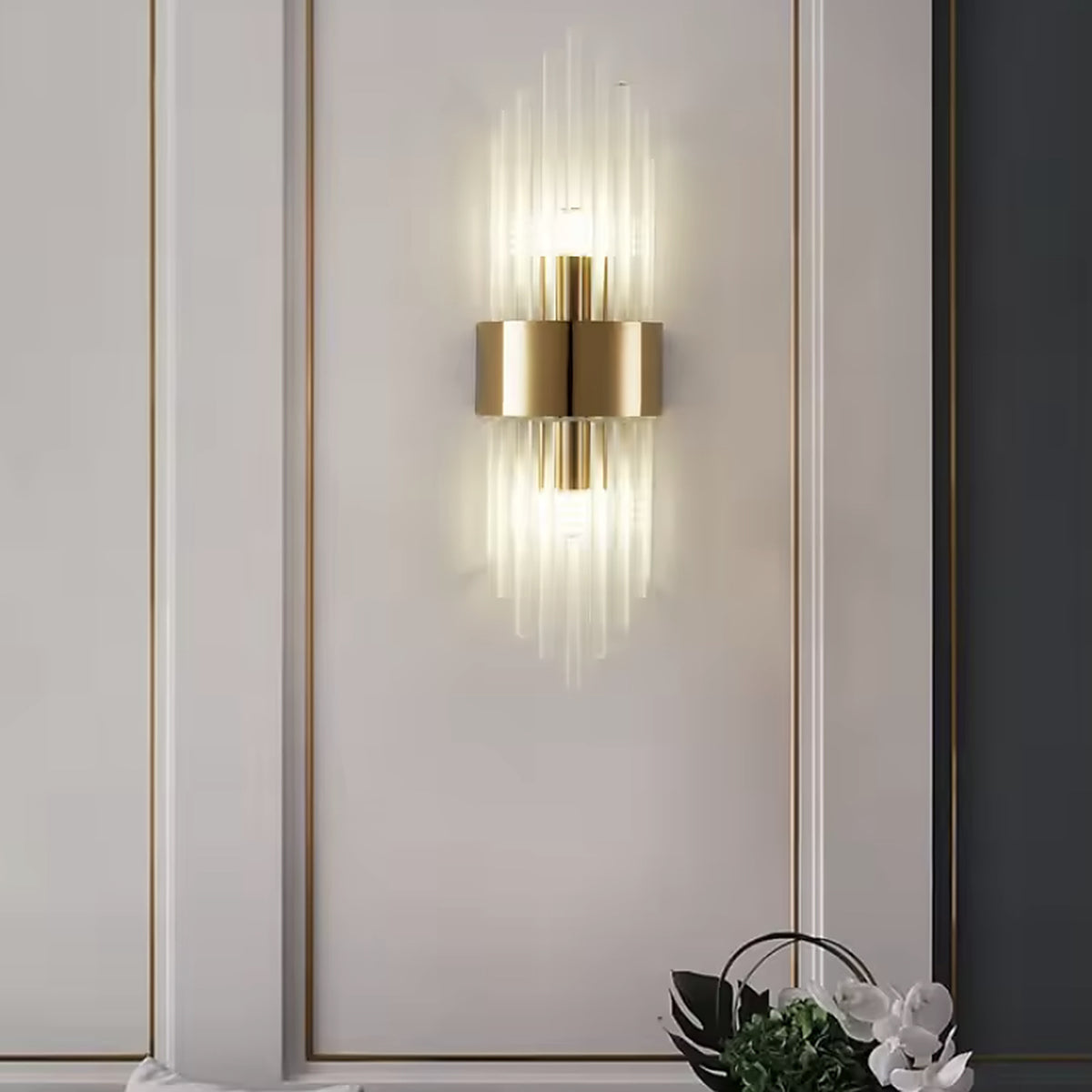 Gold linear glass rod wall sconce on a panelled wall above a green sofa