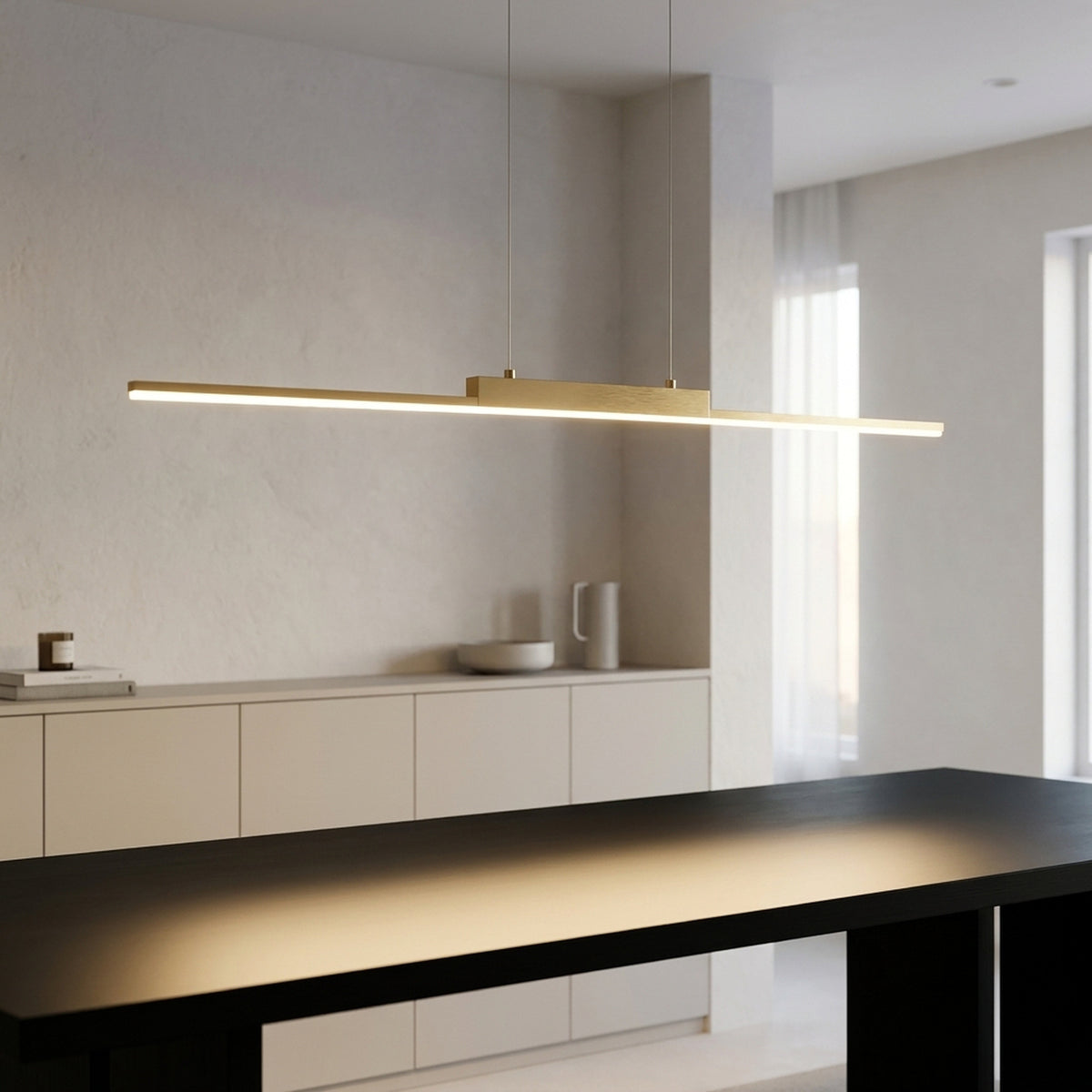 Gold linear LED chandelier switched on above a black dining table