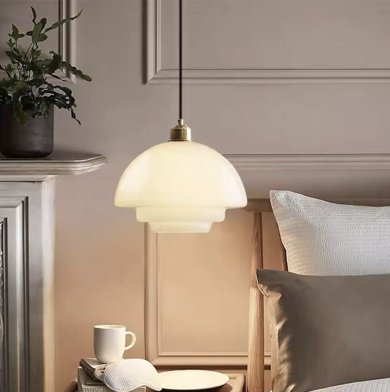 Milk glass pendant light hung beside a bed