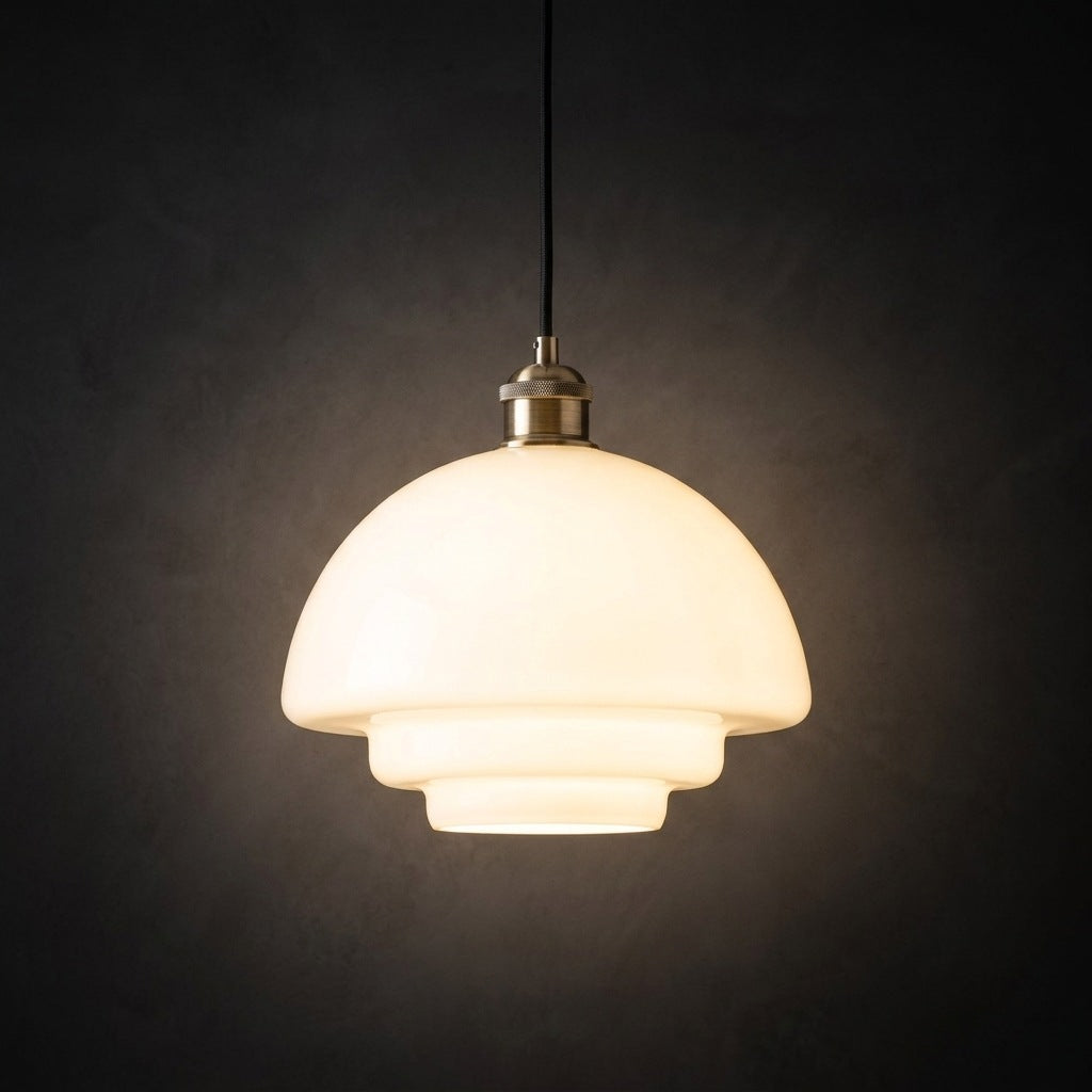Milk glass pendant light, rounded dome profile, lit against a dark plaster wall