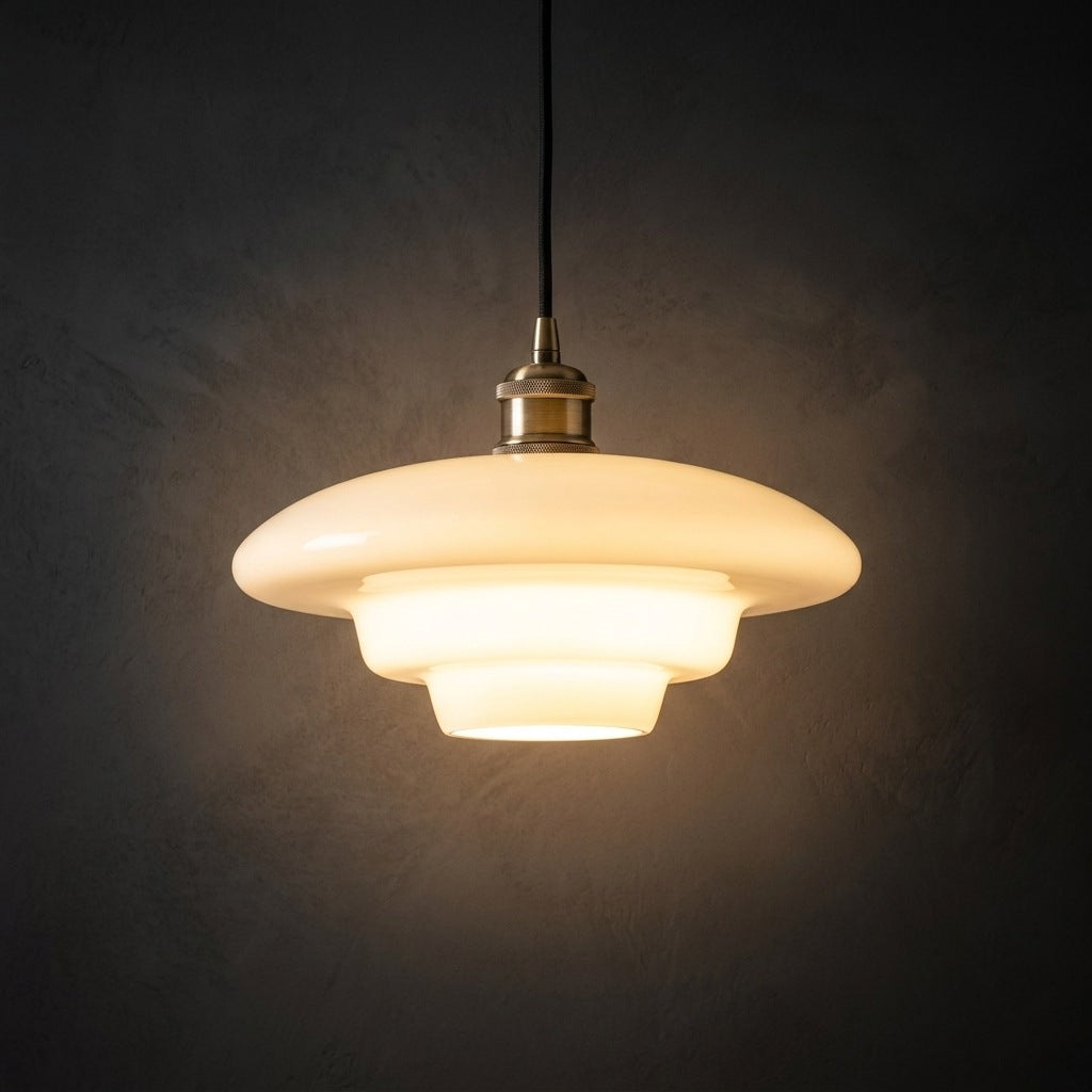 Milk glass pendant light, flat stepped profile, lit against a dark plaster wall