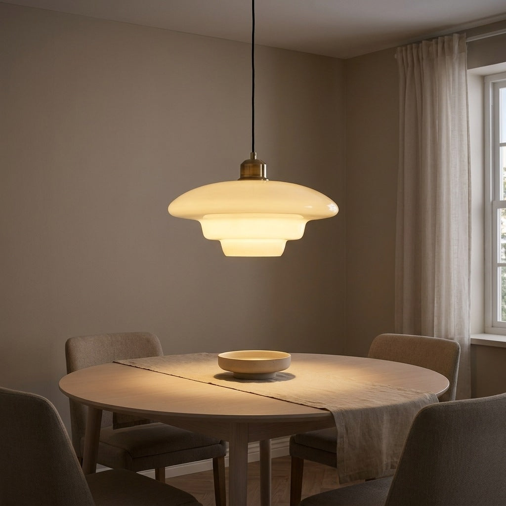 Flat profile milk glass pendant light lit above a round dining table