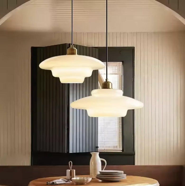 A pair of milk glass pendant lights above a round dining table