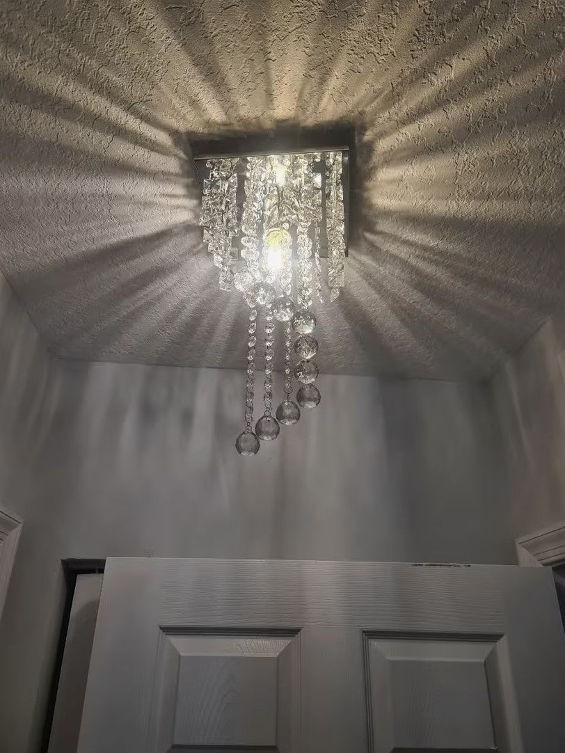 Mini crystal chandelier casting a radiating pattern on the ceiling above a door