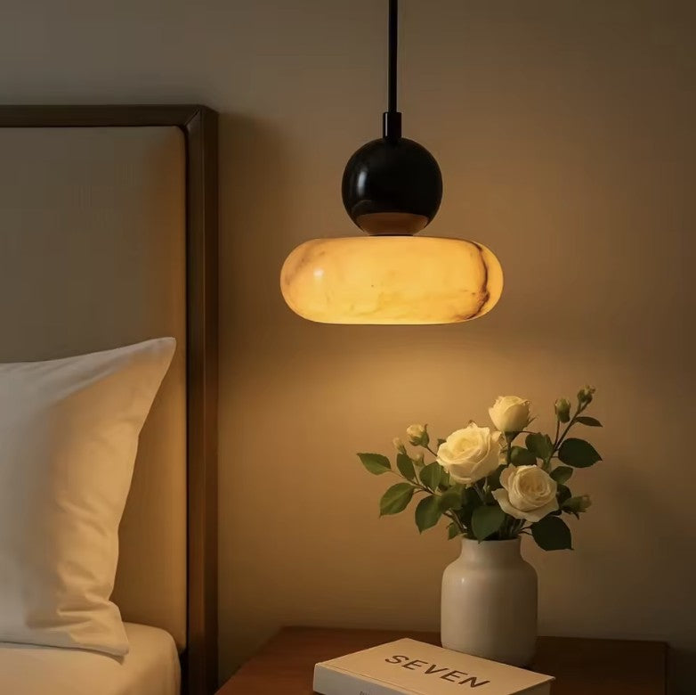 Marble mini pendant light lit above a bedside table