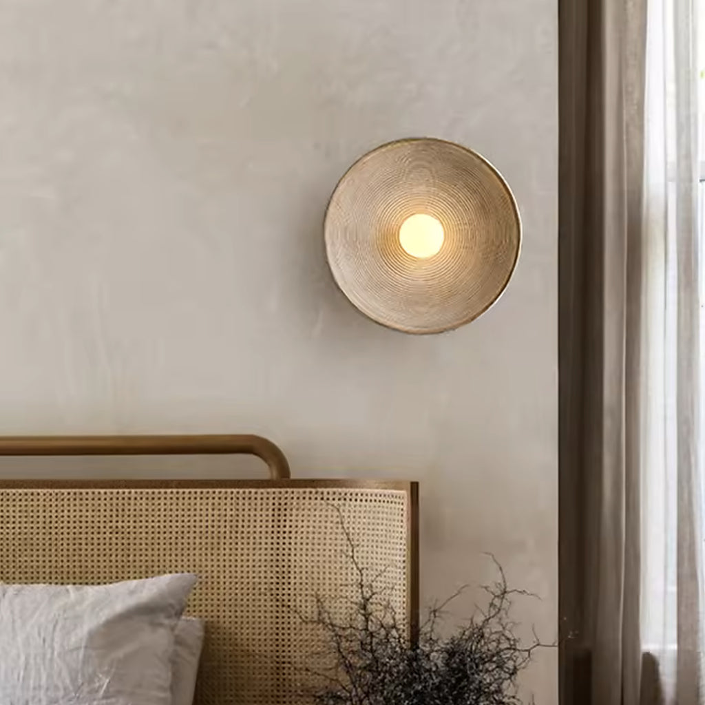 Nordic round wall sconce above a rattan headboard