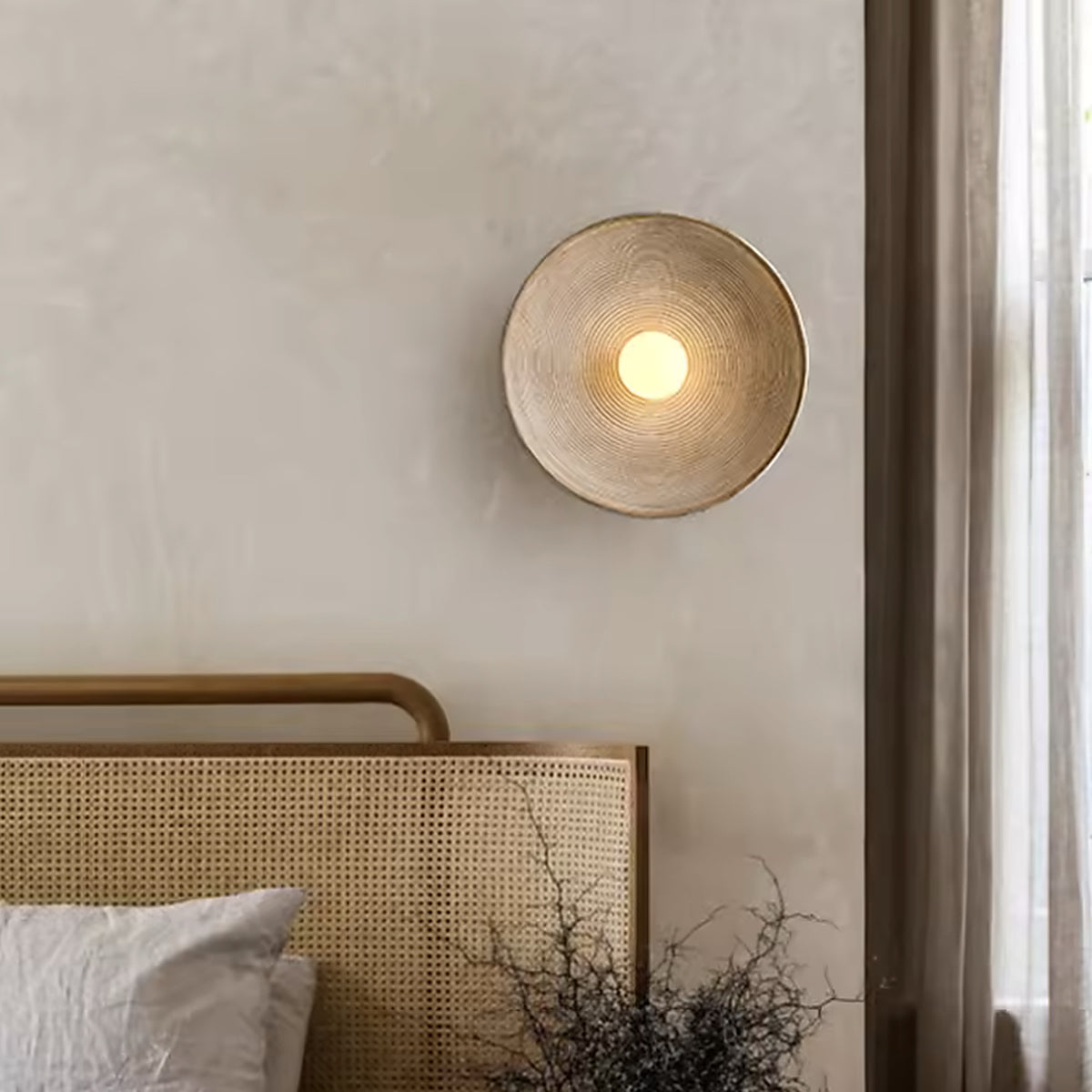 Nordic round wall sconce above a rattan headboard Image