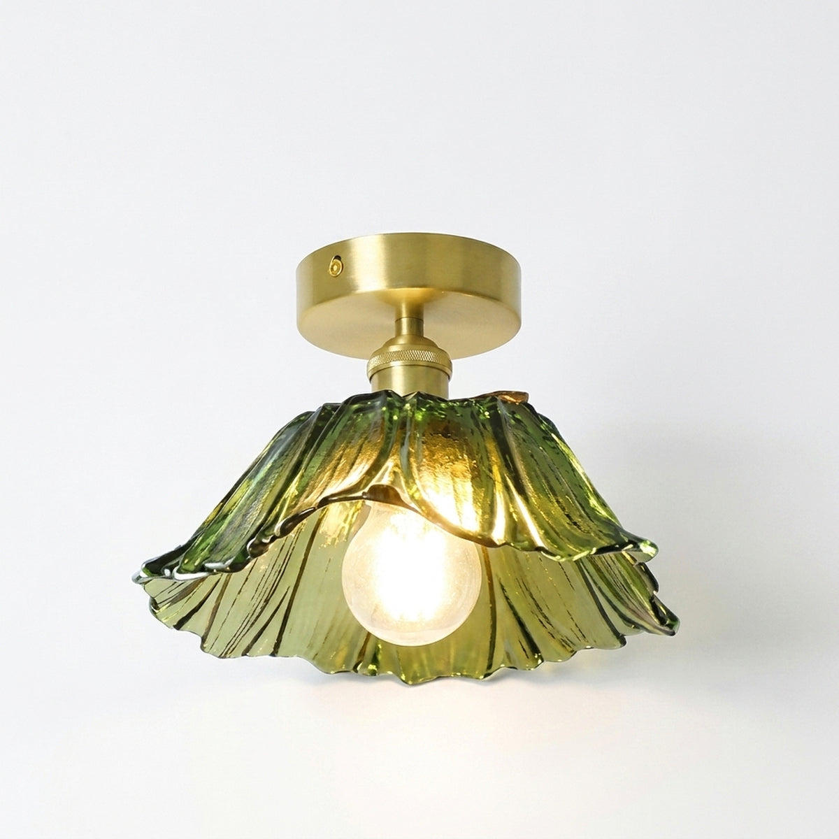 Small green ribbed glass flower flush mount ceiling light on a brass plate, switched on