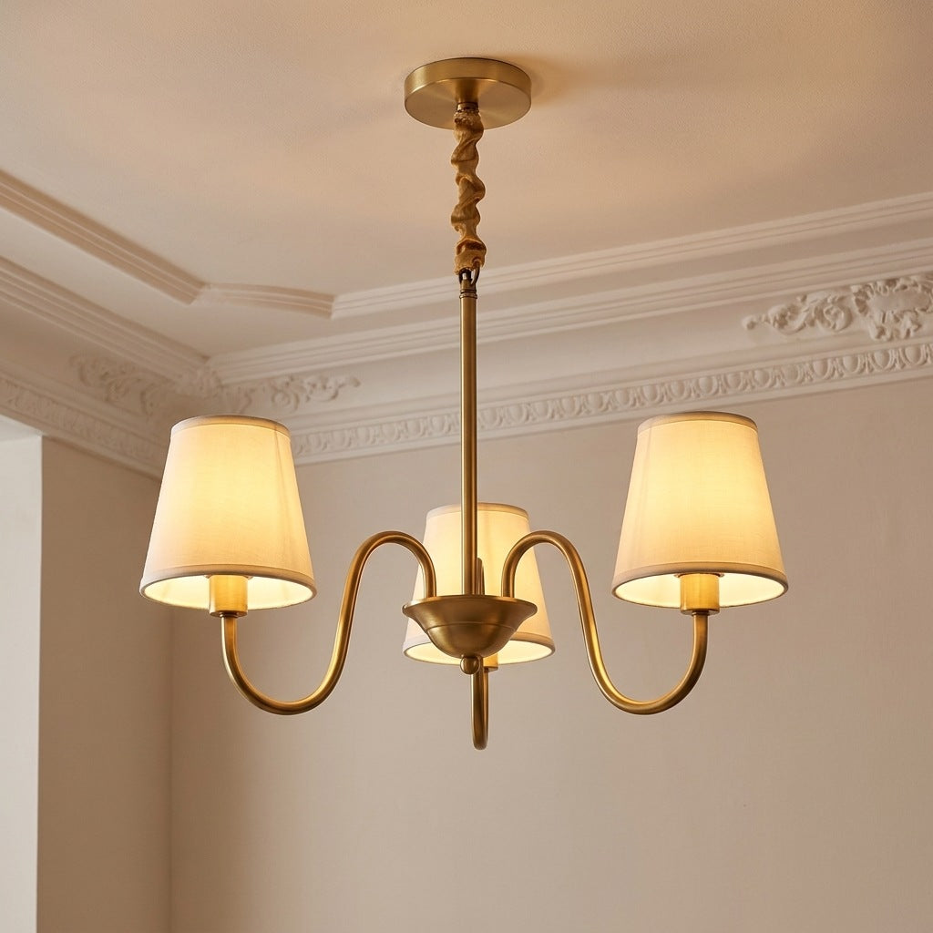 Vintage brass chandelier with 3 ivory fabric shades lit on a moulded ceiling, 24.8 inches across