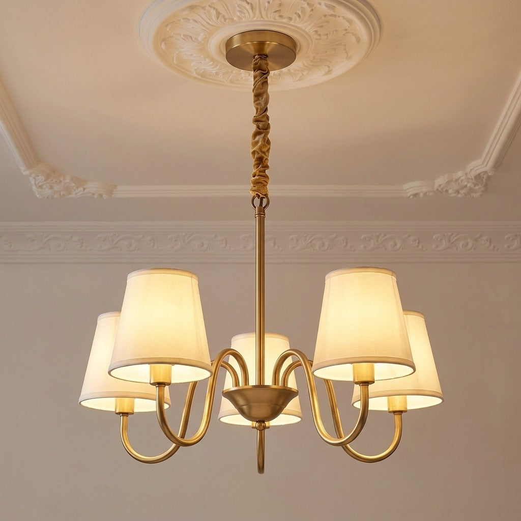 Vintage brass chandelier with 5 ivory fabric shades lit on a moulded ceiling, 24.8 inches across