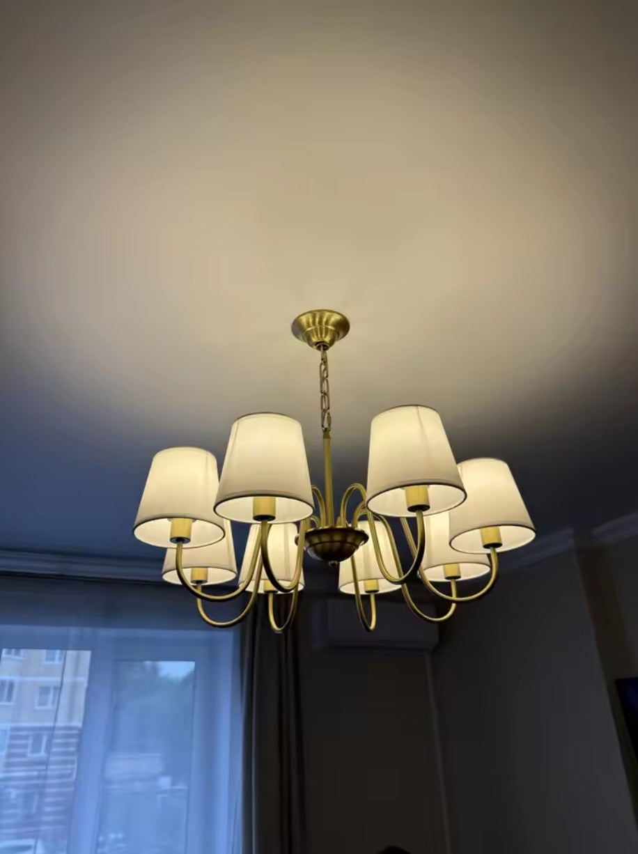 Vintage brass chandelier with six fabric shades on a white panelled ceiling
