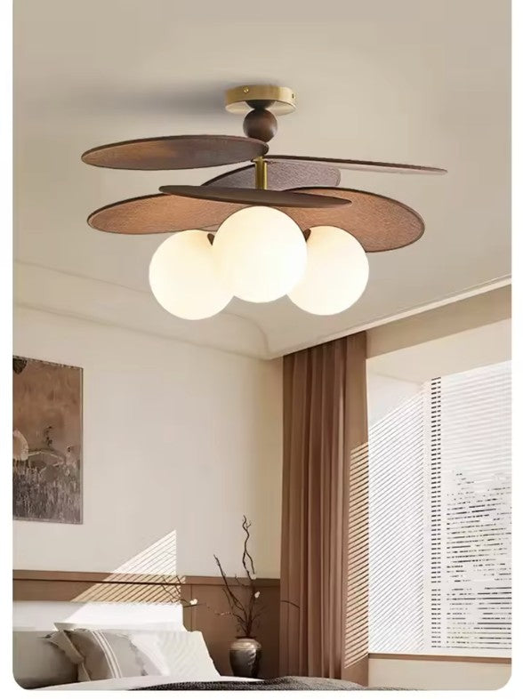 Walnut disc pendant light with three opal glass globes in a bedroom